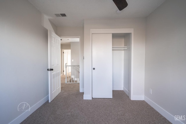 unfurnished bedroom with ceiling fan, carpet floors, a closet, and a textured ceiling