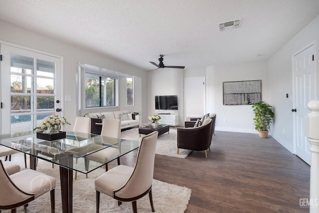 dining room featuring ceiling fan, dark wood-type flooring, and a textured ceiling