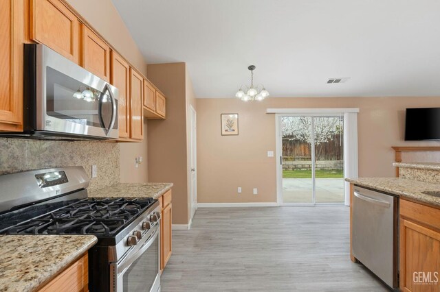 3406 Kimmie Rachelle Ct, Bakersfield, CA 93313 - kitchen featuring appliances with stainless steel finishes, decorative backsplash, light wood-style floors, a chandelier, and baseboards