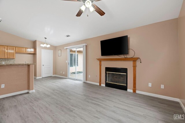 3406 Kimmie Rachelle Ct, Bakersfield, CA 93313 - unfurnished living room featuring vaulted ceiling, light wood-type flooring, a ceiling fan, a glass covered fireplace, and a chandelier