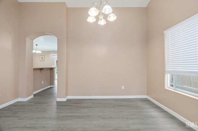 3406 Kimmie Rachelle Ct, Bakersfield, CA 93313 - unfurnished room with a chandelier, arched walkways, wood finished floors, and baseboards
