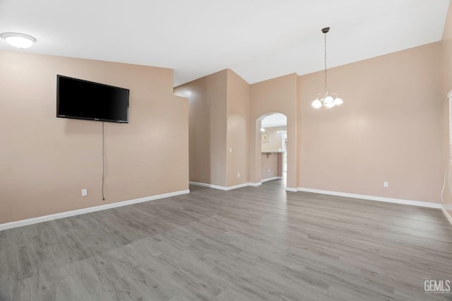 3406 Kimmie Rachelle Ct, Bakersfield, CA 93313 - unfurnished living room with arched walkways, wood finished floors, a chandelier, baseboards, and high vaulted ceiling