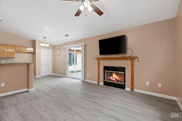 3406 Kimmie Rachelle Ct, Bakersfield, CA 93313 - unfurnished living room with vaulted ceiling, light wood-style floors, a glass covered fireplace, a ceiling fan, and a chandelier