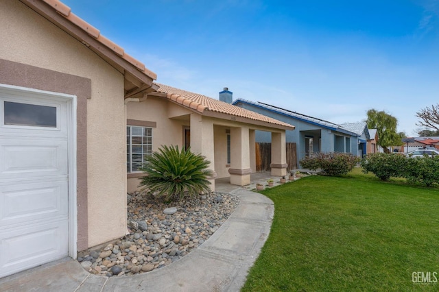 3406 Kimmie Rachelle Ct, Bakersfield, CA 93313 - view of exterior entry with a tile roof, stucco siding, a yard, and an attached garage
