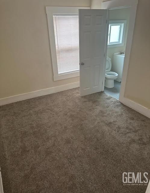 unfurnished bedroom with washer and clothes dryer, carpet floors, and connected bathroom