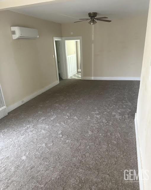 empty room featuring ceiling fan and a wall mounted air conditioner