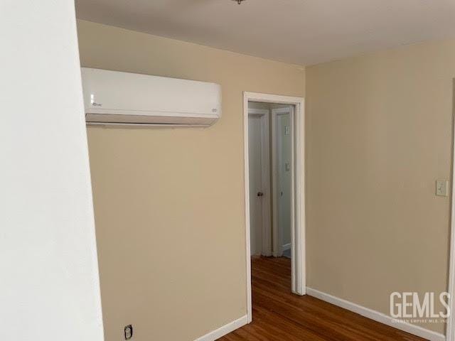 unfurnished bedroom featuring dark hardwood / wood-style floors, an AC wall unit, and a closet