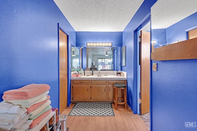 bathroom featuring a textured ceiling, vanity, wood finished floors, and a textured wall