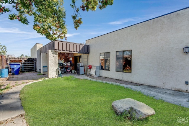 rear view of property with a lawn and stucco siding