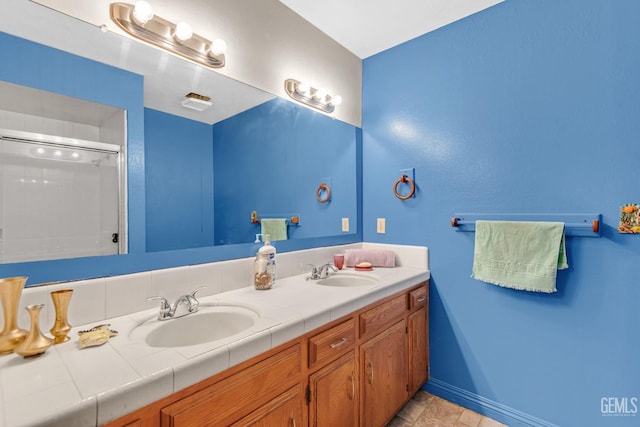 full bathroom featuring walk in shower, a sink, baseboards, and double vanity