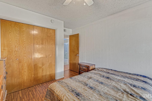 bedroom featuring a textured ceiling, wood finished floors, visible vents, a ceiling fan, and a closet