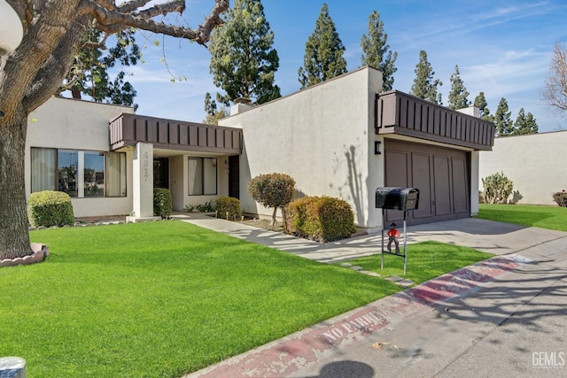 view of front facade featuring driveway, a front yard, and stucco siding