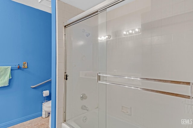 bathroom with enclosed tub / shower combo, tile patterned flooring, toilet, and baseboards