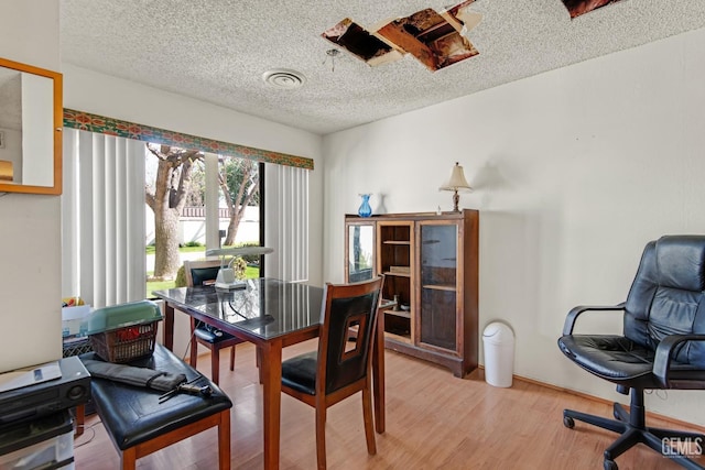 dining room with a textured ceiling, light wood finished floors, and visible vents