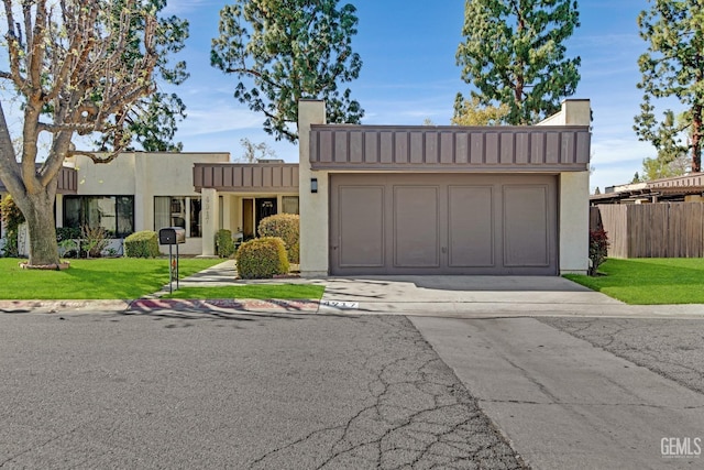 view of front of property featuring an attached garage, driveway, stucco siding, a front lawn, and a chimney