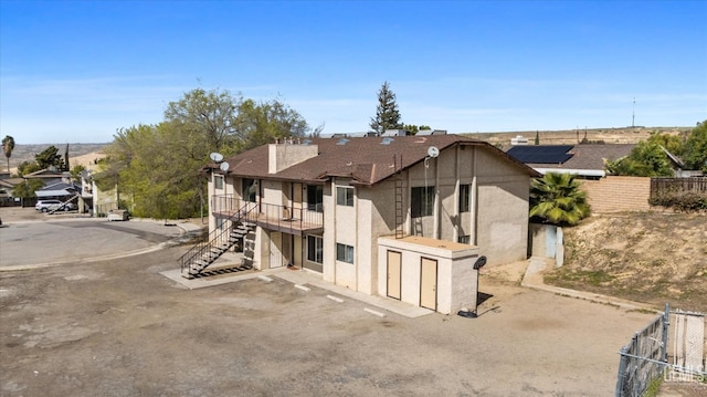 view of front of property featuring stairway, a wooden deck, stucco siding, and fence