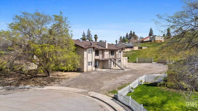 exterior space featuring stucco siding, fence private yard, driveway, and stairway