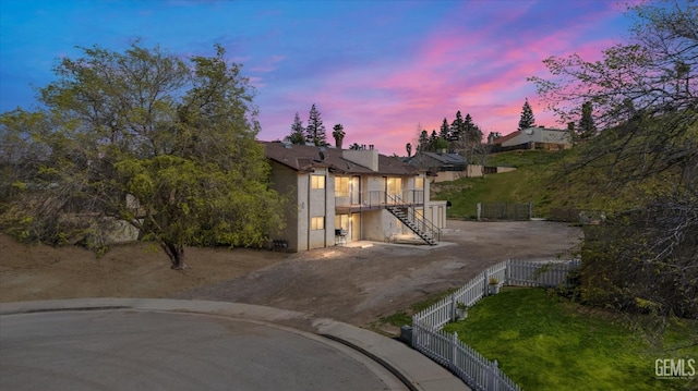 view of front facade with driveway, a fenced backyard, stucco siding, stairs, and a lawn