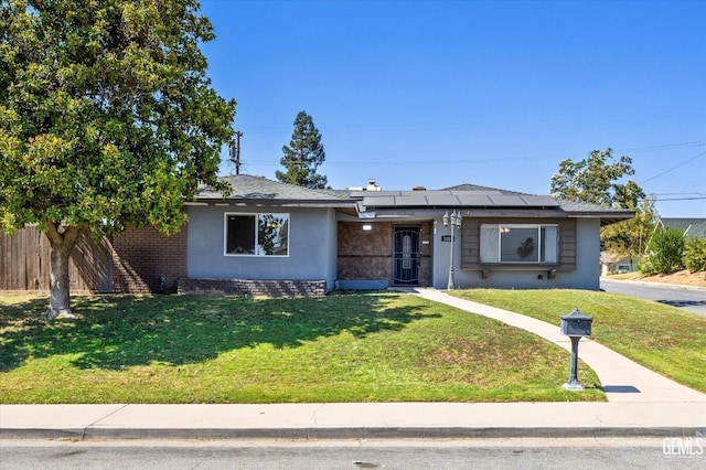 single story home with a front yard and solar panels