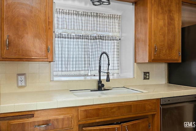 kitchen featuring tasteful backsplash, tile counters, dishwasher, and sink