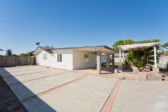 rear view of property with ceiling fan and a patio area