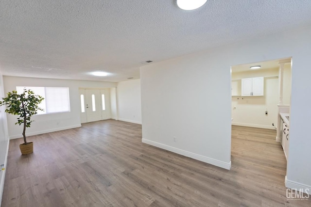 unfurnished room featuring a textured ceiling and light wood-type flooring