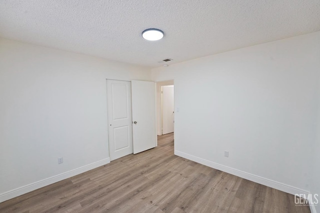 empty room with light hardwood / wood-style floors and a textured ceiling