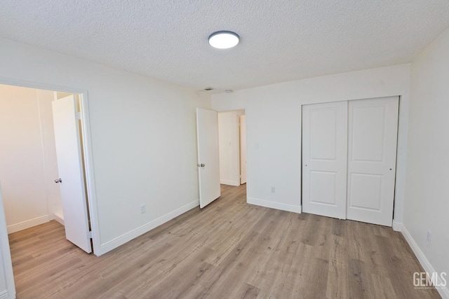 unfurnished bedroom featuring a textured ceiling, light hardwood / wood-style floors, and a closet