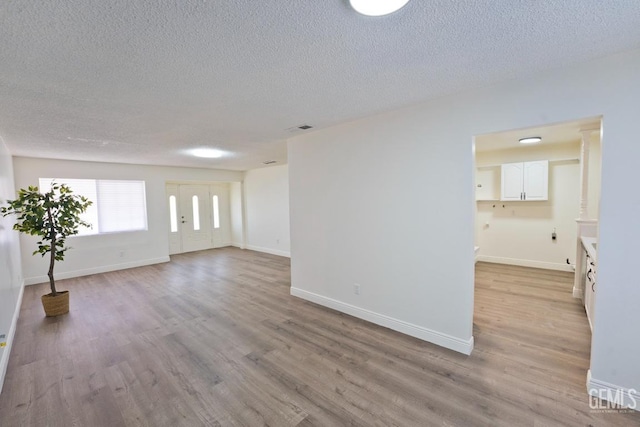 unfurnished room with a textured ceiling and light hardwood / wood-style flooring