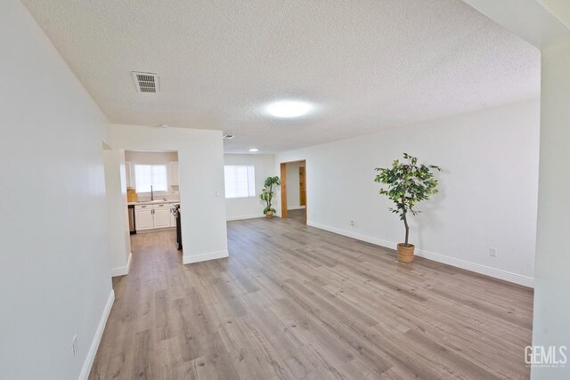 unfurnished living room featuring light wood-type flooring and a textured ceiling