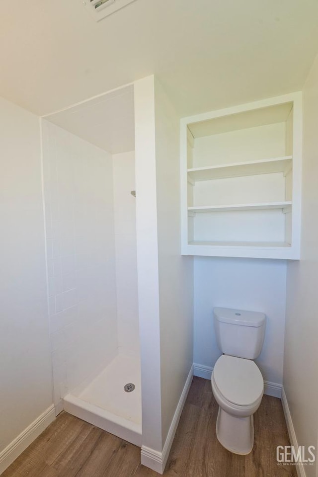 bathroom featuring walk in shower, built in shelves, toilet, and hardwood / wood-style flooring