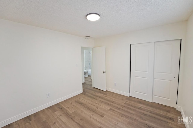 unfurnished bedroom featuring wood-type flooring, a textured ceiling, and a closet