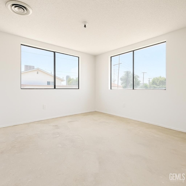 3804 University Ave, Bakersfield, CA 93306 - unfurnished room featuring healthy amount of natural light, concrete floors, a textured ceiling, and baseboards