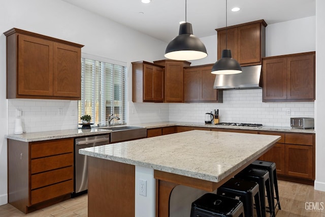 9003 Del Palma Dr, Bakersfield, CA 93314 - kitchen with stainless steel appliances, exhaust hood, light wood finished floors, a center island, and a breakfast bar