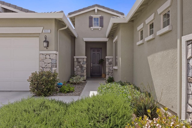 9003 Del Palma Dr, Bakersfield, CA 93314 - view of exterior entry with an attached garage, stone siding, and stucco siding