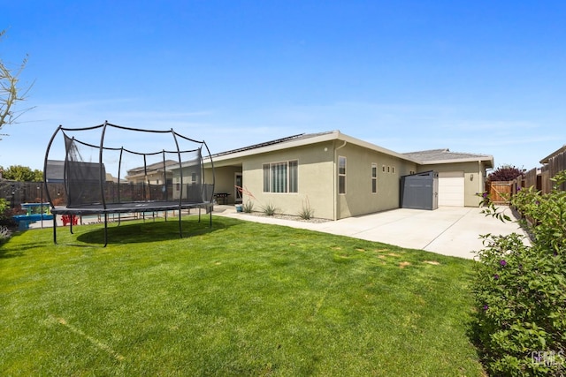 9003 Del Palma Dr, Bakersfield, CA 93314 - back of house with a trampoline, a fenced backyard, stucco siding, and roof mounted solar panels