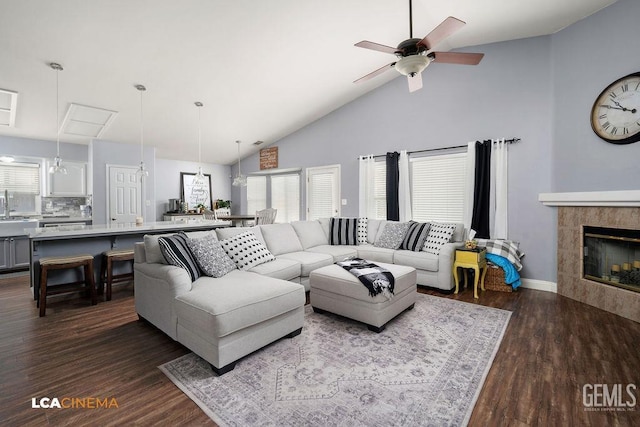 living room with ceiling fan, dark wood-type flooring, a tile fireplace, and lofted ceiling