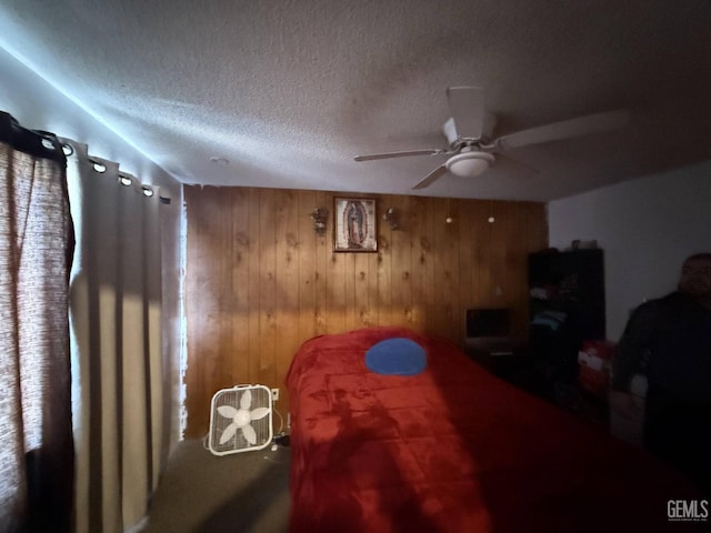 bedroom featuring ceiling fan, a textured ceiling, and wood walls