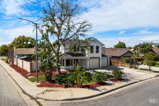 view of front facade featuring board and batten siding, concrete driveway, a garage, and fence