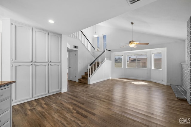 unfurnished living room with dark wood-style floors, a brick fireplace, stairs, and vaulted ceiling