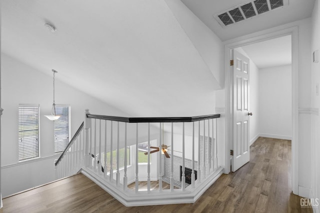 hall featuring wood finished floors, an upstairs landing, visible vents, and lofted ceiling