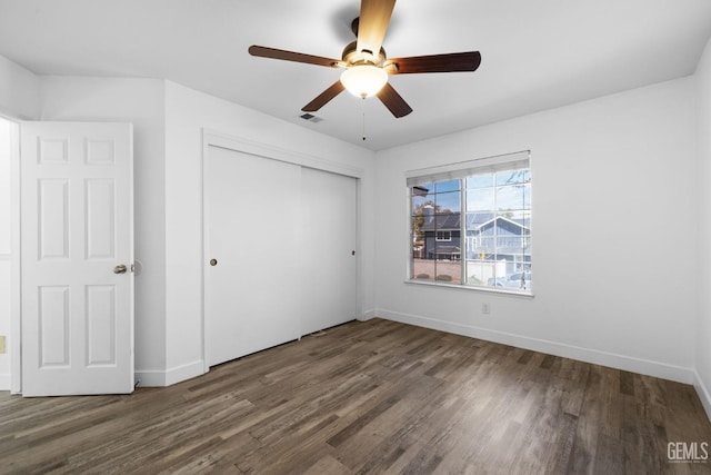 unfurnished bedroom featuring visible vents, baseboards, wood finished floors, a closet, and a ceiling fan