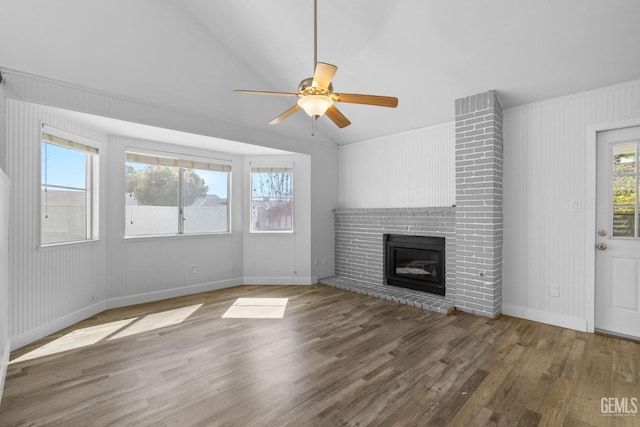 unfurnished living room featuring a ceiling fan, wood finished floors, baseboards, lofted ceiling, and a brick fireplace