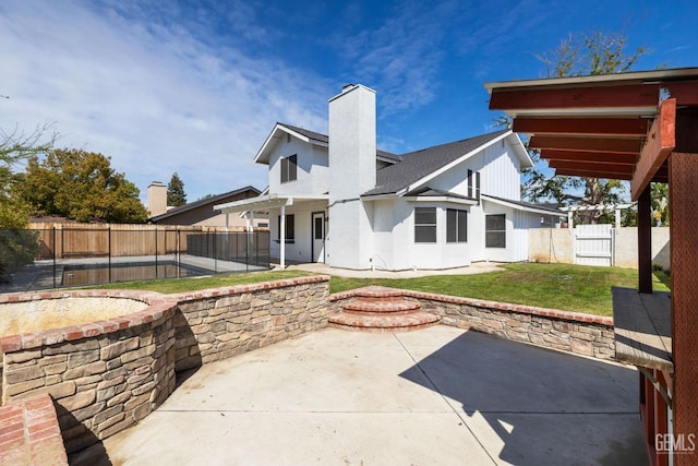 rear view of property featuring a patio, a yard, a fenced backyard, and a chimney