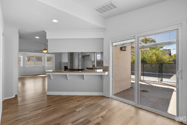 kitchen featuring visible vents, a peninsula, a breakfast bar area, and wood finished floors