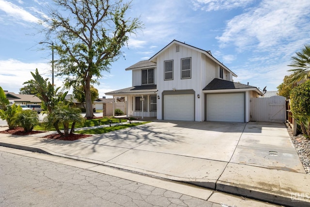 view of front facade with board and batten siding, fence, driveway, an attached garage, and a gate