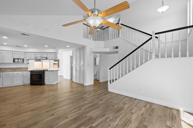 unfurnished living room featuring stairs, recessed lighting, wood finished floors, and visible vents