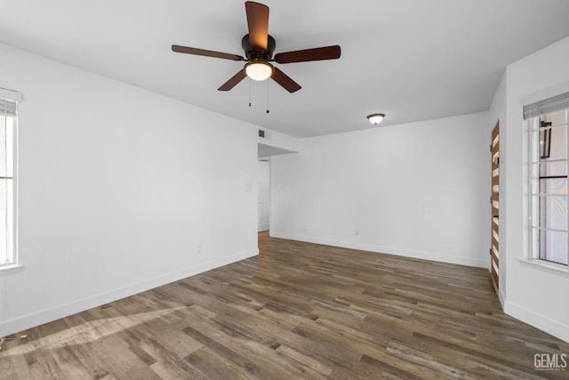 empty room with visible vents, ceiling fan, baseboards, and wood finished floors