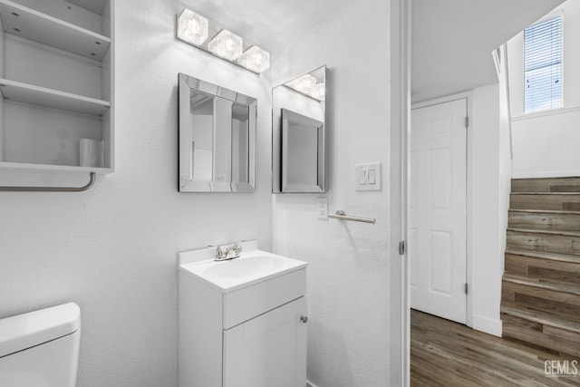 half bathroom featuring vanity, toilet, and wood finished floors