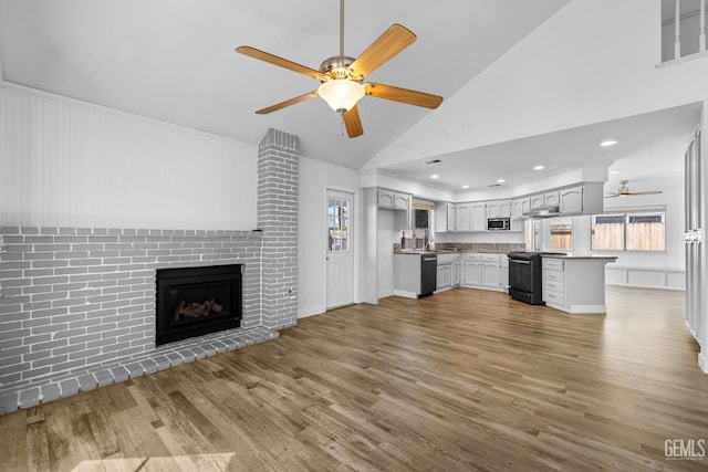 unfurnished living room with a brick fireplace, ceiling fan, recessed lighting, wood finished floors, and a sink